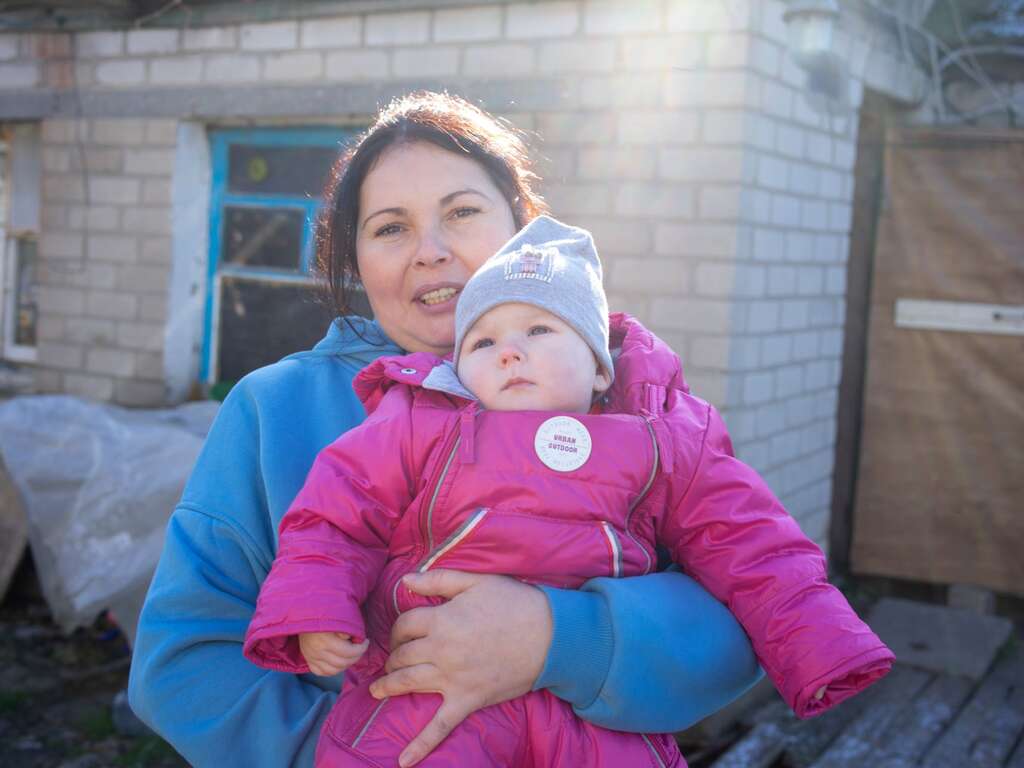 A Ukrainian woman holds her infant daughter bundled in warm winter clothes.