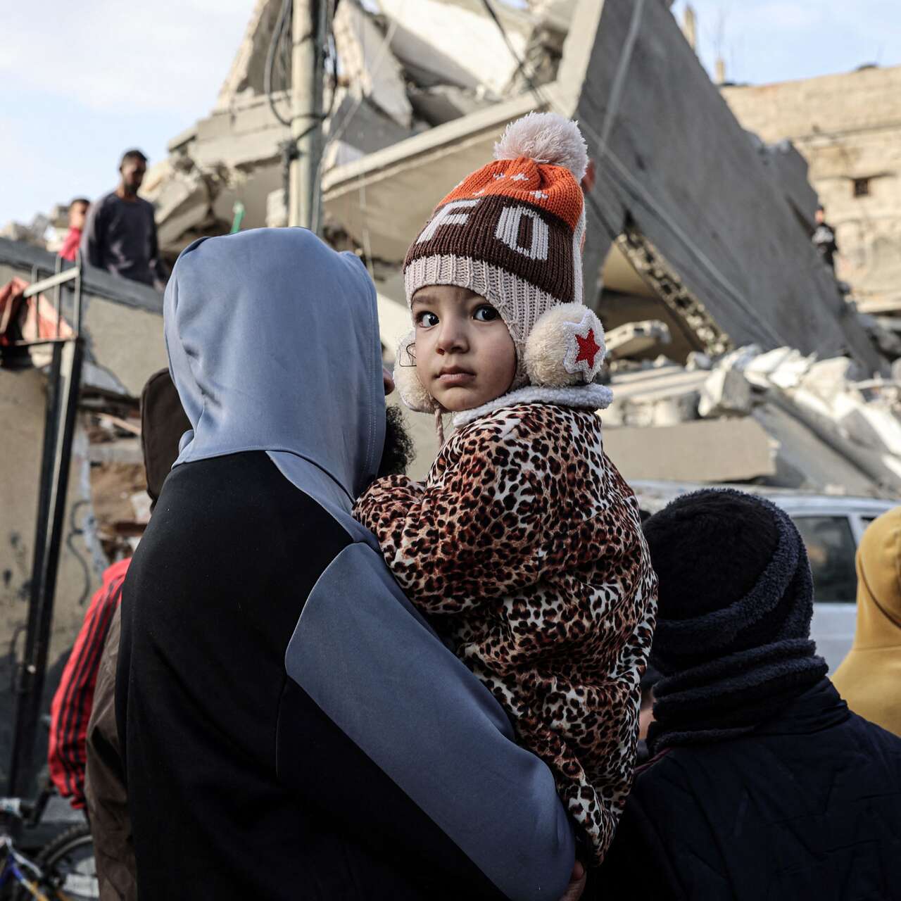 A child looks on as people sift through rubble of a home destroyed in Rafah in the southern Gaza Strip.